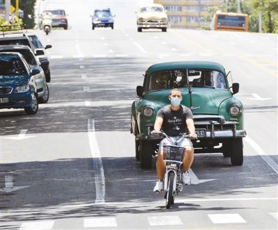 Фотода 9 тамыз күні Гаванада бір ер адам бетперде киіп кетіп барады.